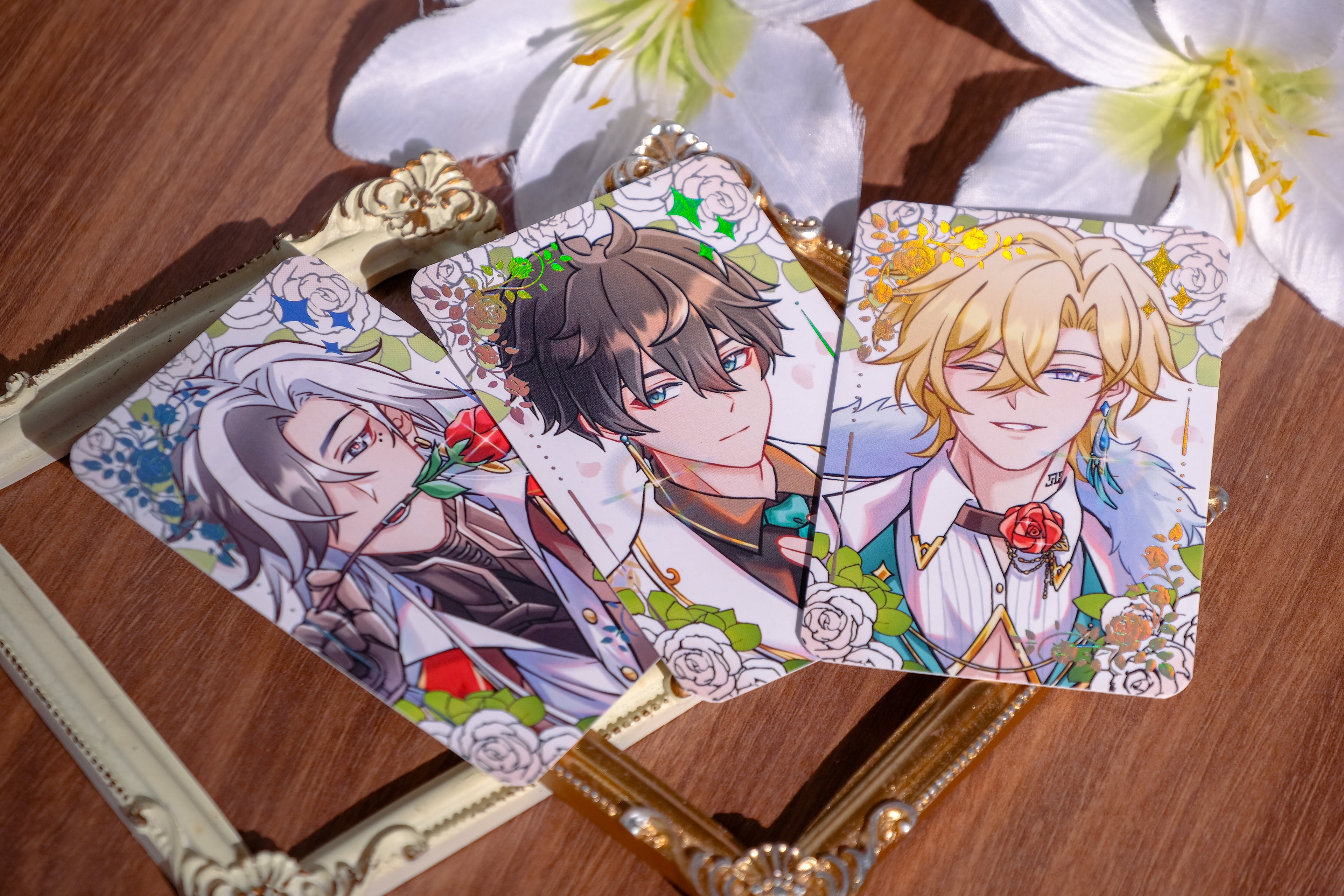 Three illustrated character cards on a wooden surface with flowers.
