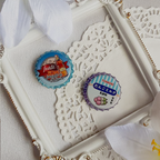 Two bottle caps on a decorative white surface with intricate patterns